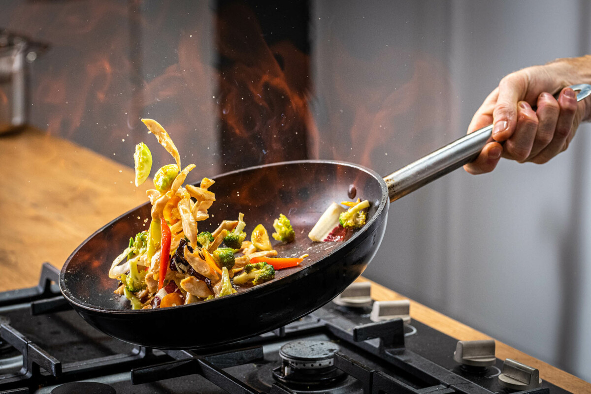 Chef tossing sauteed vegetables in a pan